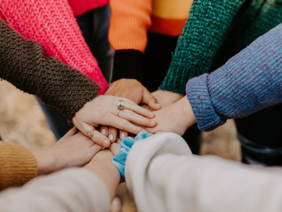 Circle of hands on top of each other. Credit: Unsplash