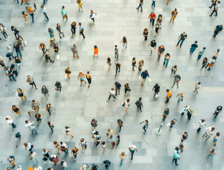 Overhead image of a crowd of people walking in a large tiled space. Credit: AdobeStock