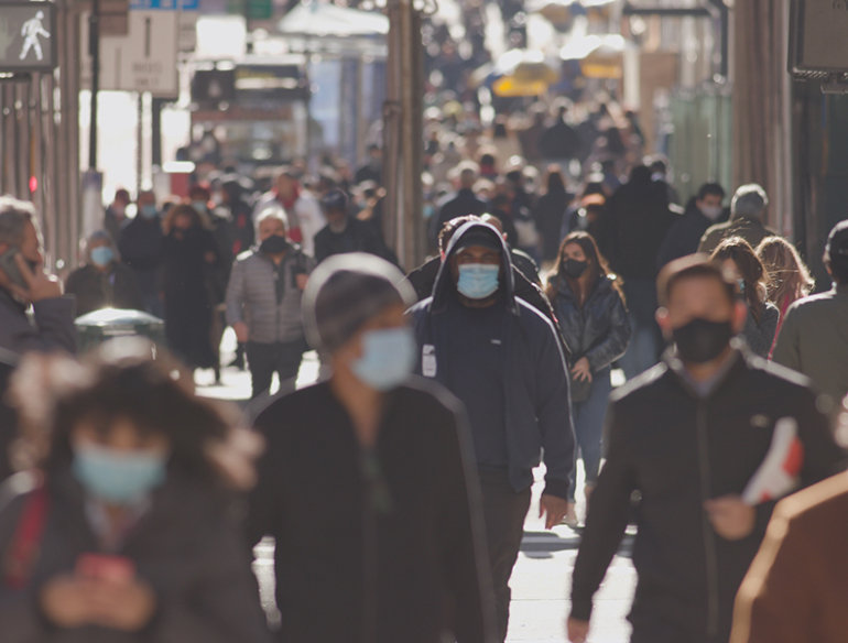 Anonymous crowd of people walking street wearing masks during covid 19 coronavirus pandemic