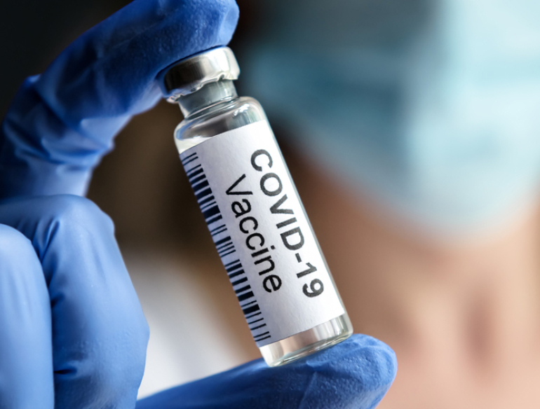 Gloved hand holding a COVID-19 vaccine vial. Credit: Shutterstock