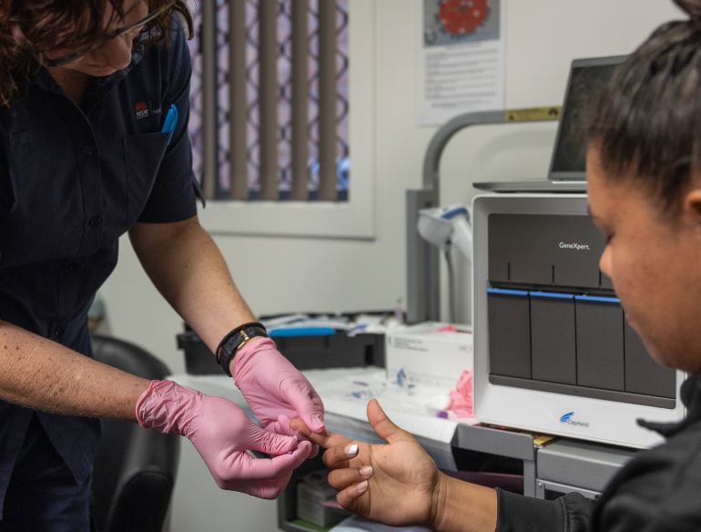 Woman nurse examining finger of Aboriginal woman at a clinic. Credit: Thunderbox Films