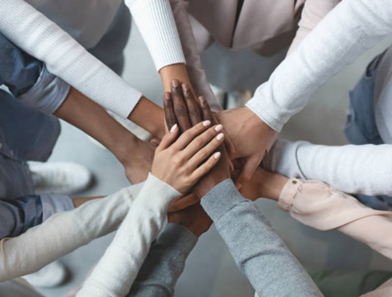 Business team putting hands together on top of each other stock photo Credit: iStock