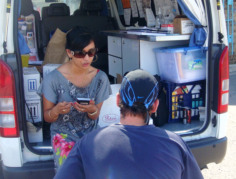 Researcher conducting interview with a community member from the back of a van. 