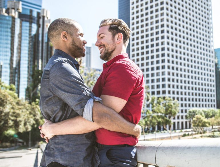 Two men hugging, gay couple, outdoors. Credit: AdobeStock