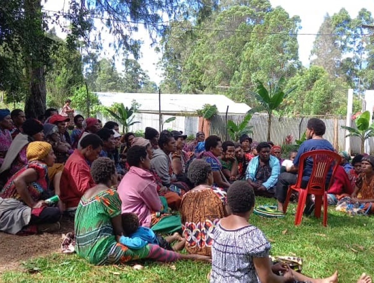 Women sitting on the ground, listening to a practitioner talk about HPV testing, cervical screening programs, in Papua New Guinea.