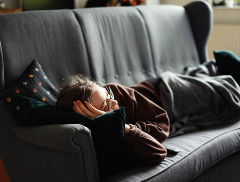 tired fatigued woman lying on couch fatigue COVID