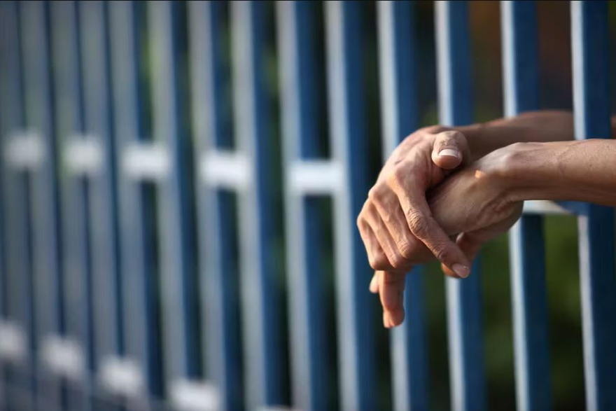 Hands through jail cell bars