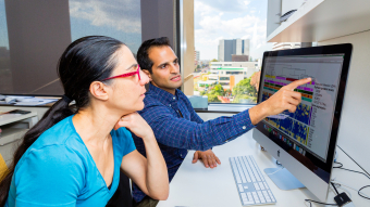 Staff from Viral Immunology Systems Program looking and pointing at a computer monitor with colourful graphs on it. Credit: Kirby Institute/Bec Lewis.