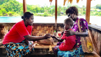 Woman giving medication to a child and mother, Solomon Islands.