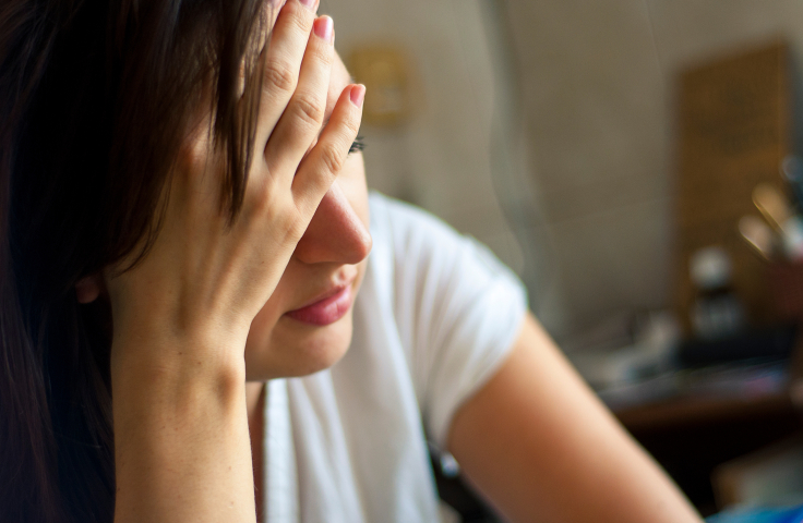 Tired looking woman with hand against forehead