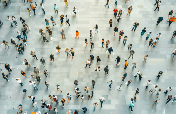 Overhead image of a crowd of people walking in a large tiled space. Credit: AdobeStock
