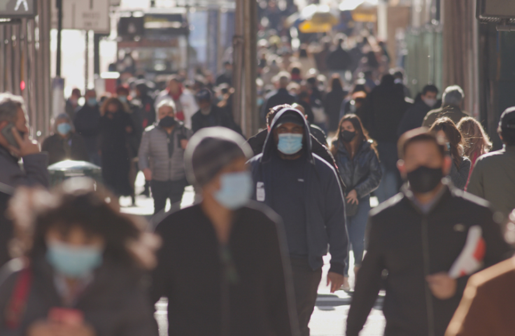 Anonymous crowd of people walking street wearing masks during covid 19 coronavirus pandemic