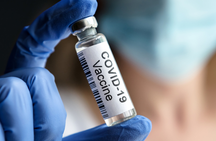 Gloved hand holding a COVID-19 vaccine vial. Credit: Shutterstock