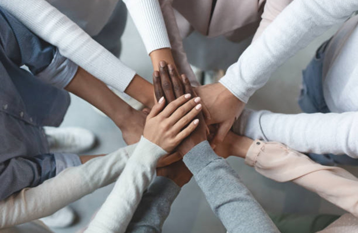 Business team putting hands together on top of each other stock photo Credit: iStock