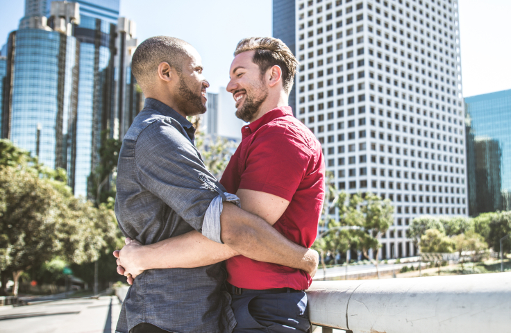 Two men hugging, gay couple, outdoors. Credit: AdobeStock