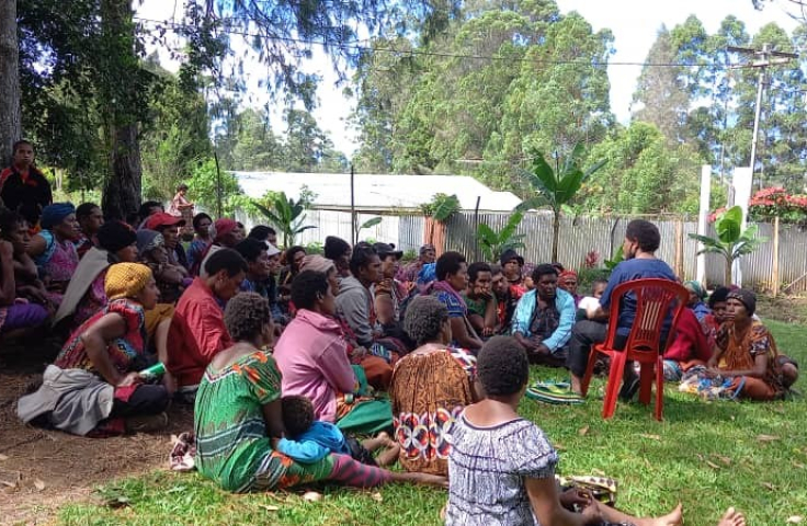 Women sitting on the ground, listening to a practitioner talk about HPV testing, cervical screening programs, in Papua New Guinea.