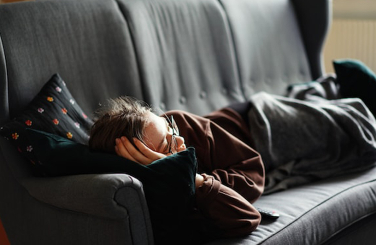 tired fatigued woman lying on couch fatigue COVID